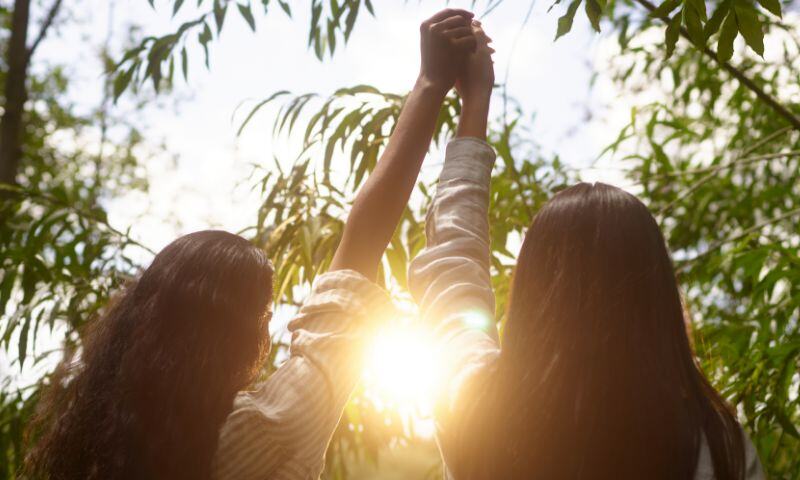 Happy, healthy friends holding hands in the sun